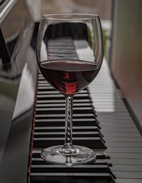 Glass of red wine on piano keyboard. Music and wine concept, Space for text, Selective focus.