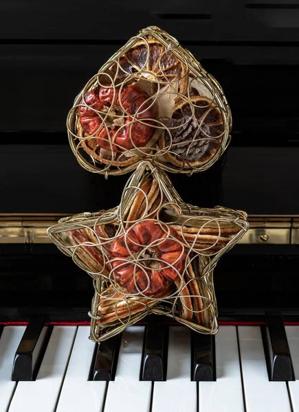 Golden heart shaped mesh case and Golden star shaped mesh case are filled with dried fruits stand on the Piano Keyboard. Christmas decoration concept, Space for text, Selective focus.