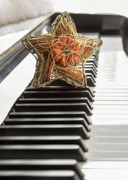Golden star shaped mesh case is filled with dried fruits stand on the Piano Keyboard. Dried fruits in star shaped metal case on keyboard, Christmas decoration, Success concept, Space for text, Selective focus.