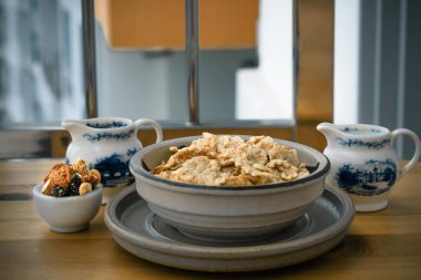Ev yapımı Gadola, Mısır gevreği ve fındıklar seramik kasede Tahta masada badem sütüyle servis ediliyor. Sağlıklı kahvaltı, kopyalama alanı, seçmeli odak.