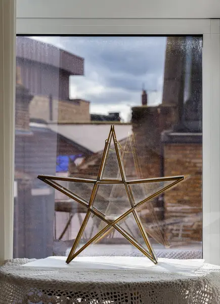 Brass Star Glass Tealight candle holder near the window. Vintage star brass shaped lamp. The art of metal & glass craftwork, Home decor, Space for text, Selective focus.