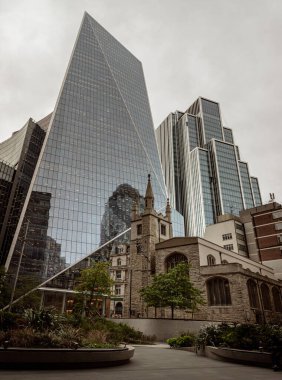 Londra, İngiltere - 23 Ekim 2023 - St. Andrew Undershaft Kilisesi modern gökdelen binalarının önünde. Klasik ve modern tasarımlara zıt olan eski ve yeni binaların mimari görüşü, metin için alan, Seçici odak.