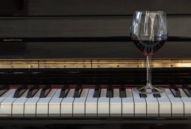 Piyano klavyesinde bir kadeh kırmızı şarap. Müzik ve şarap konsepti, boşluğu kopyala, seçici odak.