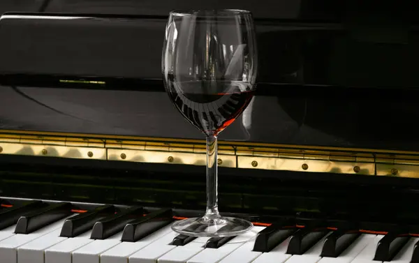 Glass of red wine on piano keyboard. Music and wine concept, Copy space, Selective focus.