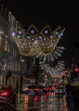 Londra, İngiltere - 25 Aralık 2023 - Noel Taç Dekorasyonları ışık gösterimine yol açtı. Alacakaranlıkta Bond caddesinde asılı geleneksel Noel dekorasyon ışıklarının dramatik manzarası, Noel Ruhu, Londra 'da Işık Festivali, Kopyalama alanı, Seçici odak