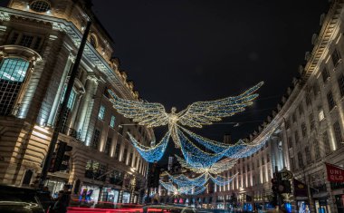 Londra, İngiltere - 25 Aralık 2023 - Uçan melek Noel süslemesi ışık gösterimine öncülük etti. Alacakaranlıkta Regent Caddesi üzerinde asılı geleneksel Noel süsleme ışıklarının dramatik manzarası, Noel Ruhu, Londra 'da Işık Festivali, metin için alan,
