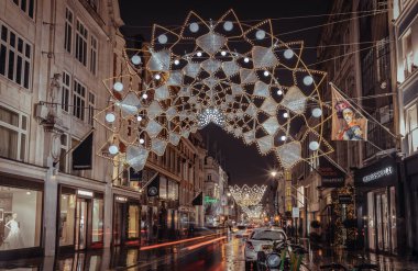 Londra, İngiltere - 25 Aralık 2023 - Noel taçlarının süslemeleri ışık sergisi açtı. Alacakaranlıkta Bond caddesinde asılı geleneksel Noel dekorasyon ışıklarının dramatik manzarası, Noel Ruhu, Londra 'da Işık Festivali, metin için alan, 