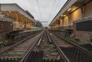Londra, İngiltere - 25 Aralık 2023 - Boş demiryolu rayları ve elektrik altyapı ekipmanlarına perspektif görüşü, Acton merkez tren istasyonunda kablolar. Tren platformu, taşımacılık ve nakliye alanlarının Metal çerçevelerine sahip demiryolu sistemi, 