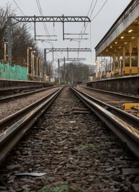 Londra, İngiltere - 25 Aralık 2023 - Düşük perspektiften demiryolu rayları. Odak derinliği sınırlı demiryolu rayları, Demiryolu platformunun metal çerçeveli demiryolu sistemi, raylar, tren rayları, tren istasyonu, mesaj için yer, Selecti