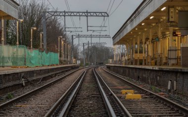 Londra, İngiltere - 25 Aralık 2023 - Boş demiryolu rayları ve elektrik altyapı ekipmanlarına perspektif görüşü, Acton merkez tren istasyonunda kablolar. Tren platformu, taşımacılık ve nakliye alanlarının Metal çerçevelerine sahip demiryolu sistemi, 