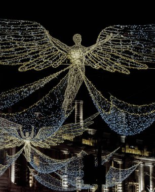 Londra, İngiltere - 25 Aralık 2023 - Uçan melek Noel süslemesi ışık gösterimine öncülük etti. Alacakaranlıkta Regent Caddesi üzerinde asılı geleneksel Noel süsleme ışıklarının dramatik manzarası, Noel Ruhu, Londra 'da Işık Festivali, metin için alan,