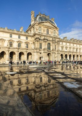 Fransa, Paris - Ocak 03, 2024 - Paris 'teki Louvre Müzesi' ne yağmur yağdıktan sonra su yansıtma efektiyle tarihi saray manzarası. Paris 'teki dünyanın en büyük müzelerinden biri, metin için alan, seçici odak.