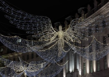 Londra, İngiltere - 25 Aralık 2023 - Uçan melek Noel süslemesi ışık gösterimine öncülük etti. Alacakaranlıkta Regent Caddesi üzerinde asılı geleneksel Noel süsleme ışıklarının dramatik manzarası, Noel Ruhu, Londra 'da Işık Festivali, metin için alan,