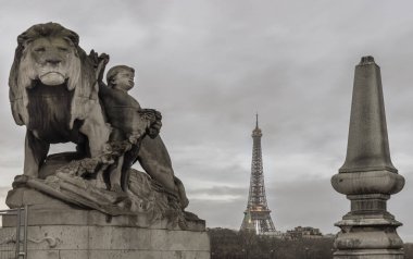 Fransa, Paris - Ocak 04, 2024 - Eyfel Kulesi 'nin ön planda Aslan ve Çocuk Heykeli heykeli bulunan Pont Alexandre-III köprüsünden akşam manzarası. Paris 'in en ikonik simgelerinden biridir, metin için alan, seçici odak.