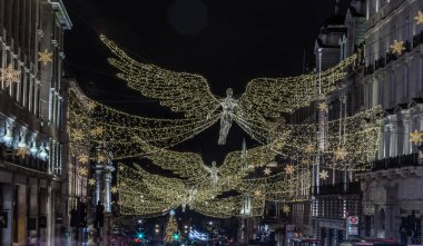 Londra, İngiltere - 25 Aralık 2023 - Uçan melek Noel süslemesi ışık gösterimine öncülük etti. Alacakaranlıkta Regent Caddesi üzerinde asılı geleneksel Noel süsleme ışıklarının dramatik manzarası, Noel Ruhu, Londra 'da Işık Festivali, metin için alan,
