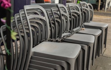 Güneşli bir günde gümüş gri plastik sandalyeler kafe terasının yanındadır. Desenli yığın plastik sandalyeler, metin için boşluk, seçici odak.
