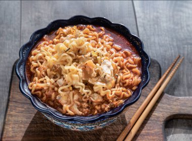 Yumurta ve seramik kasede arpacık soğanı ve tahta kesme tahtasının üzerinde baharatlı Tom yum eriştesi. Kolay erişte yiyecekler, üstten gizli görüş, boşluğu kopyalamak, seçici odaklanma..