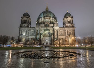 Berlin, Almanya - 19 Aralık 2023 - Berlin Katedrali manzaralı Modemer Brunnen çeşmesi akşam karanlığında ön planda. Berlin Katedrali Berlinli Dom Berlin 'de, metin için alan, seçici odak.
