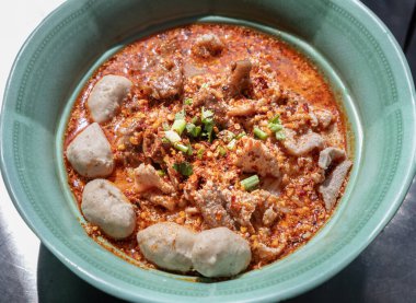 Baharatlı Tom yum pilavlı erişte (Tayland baharatlı çorbası), haşlanmış domuz eti (güveç domuz eti), kişniş, doğranmış soğan ve yeşil seramik kasede biber serpiştirilmiş taze domuz ve domuz topları. Metin için boşluk, Seçici odak.