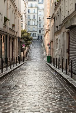 Fransa, Paris - Ocak 03, 2024 - Paris 'teki eski Montmartre caddelerinden birinin manzarası. Tipik Fransız mimarisine sahip dar bir kaldırım taşı caddesi Paris şehrindeki Montmartre 'nin tarihi bölgesinde alçalıyor ve yükseliyor.,