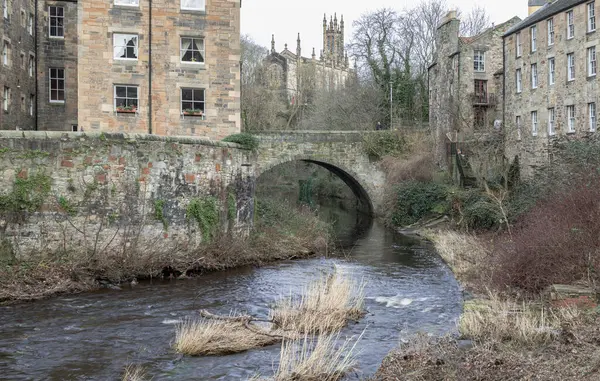 stock image Edinburgh, Scotland - Jan 16, 2024 - View from the Dean Village towards Holy Trinity Church, now the Rhema Christian Centre Church with Dean Bridge and The Water of Leith flowing through Dean Village in the foreground. Space for text, Selective focus