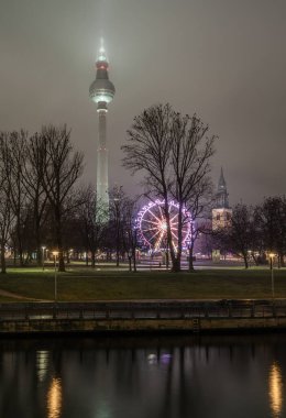 Berlin, Almanya - 19 Aralık 2023 - Ünlü Berlin Televizyon Kulesi (Fernsehturm), Mary Kilisesi Çan Kulesi ve Alexanderplatz yakınlarındaki Ferris Gece Noel Çarkıfeleği, Uzayı Kopyala, Seçici Odaklanma.