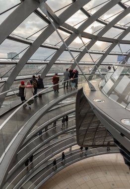 Berlin, Almanya - 20 Aralık 2023 - Çok sayıda turist gelecekteki cam kubbenin içindeki rampalarda yürüyor. Reichstag binasının içinde yukarı doğru uzanan kıvrımlı bir yürüyüş yolu var. Reichstag Kubbesi 'nin modern mimarisi. 