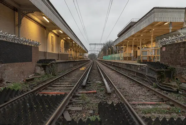 stock image London, UK - Dec 25, 2023 - Perspective view on empty railway tracks and electric infrastructure equipment, wires at Acton central rail station. The Railway system with Metal frames of Train platform, Transport and shipping landscape concept, Railroa