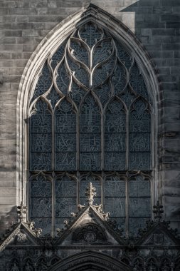 Edinburgh, İskoçya - 18 Ocak 2024 - Güneş lekeli cam kemerli pencerelerin yüzeyinden parlıyor ve Gable, Edinburgh 'daki St. Giles Katedrali' nin giriş kapısının üzerinde. High Kirk 'ün Neo-gotik' teki dış mimari detayları.. 