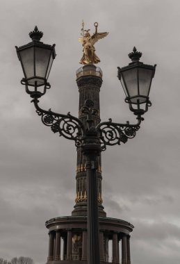 Berlin, Almanya - 20 Aralık 2023 - Arka planda zafer sütunu olan sokak lambası direği. Prusya 'nın Tiergarten' deki Fransız-Alman savaşındaki zaferini kutlamak için Tanrıça Victoria ile birlikte Zafer sütununun üst kısmında. Boşluğu kopyala, Seçici odak.