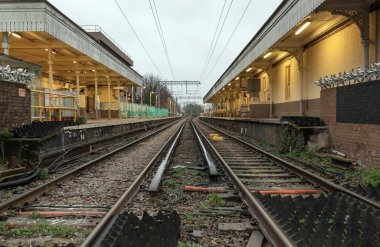 Londra, İngiltere - 25 Aralık 2023 - Boş demiryolu rayları ve elektrik altyapı ekipmanlarına perspektif görüşü, Acton merkez tren istasyonunda kablolar. Tren peronunun metal çerçeveli demiryolu sistemi, nakliye ve nakliye peyzajı konsepti, Demiryolu