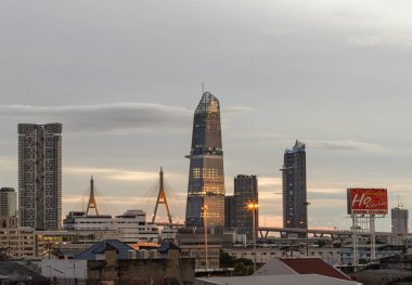 Bangkok, Tayland - 14 Ağustos 2024 Bhumibol Köprüsü 'nün simgesi Kingbridge kulesiyle şehir manzarası. Bangkok iş bölgesinin alacakaranlık siluetinde göz kamaştırıcı. Gökdelenler bunu duvar kağıdı, poster ve afiş tasarımı olarak kullanıyor.