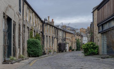 Edinburgh, İskoçya - 16 Ocak 2024 - Circus Lane manzaralı Edinburgh Stockbridge 'de güzel çiçeklerle kaplı teras evleriyle dolu bir sokak. Boşluğu kopyala, Seçici odak.