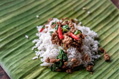 Üzerinde Tayland usulü dünyaca ünlü bir lezzet olan muz yaprağında servis edilen kıymalı Tayland fesleğeni (Pad Ka Prao Moo) ile karıştırılmış pirinç..