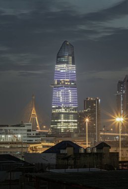 Bangkok, Tayland - 04 Aralık 2024 Kingbridge Kulesi 'nin muhteşem manzarası Bhumibol Köprüsü' nün ve Bangkok 'un iş bölgesinde gökdelenlerin sembolik simgesi ve geceleri parlayan ışıklarla birlikte. Modern binaların mimarisi,