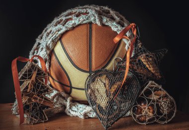 İçinde ağ örgüsü süslemesi olan basketbol topu, Noel ağacı örgüsü davası, ve karanlık arka planda Star Ağ davası. Noel temalı basketbol fikri, Noel 'de spor oyunu, bunu duvar kağıdı, poster ve boşluk olarak kullanın.
