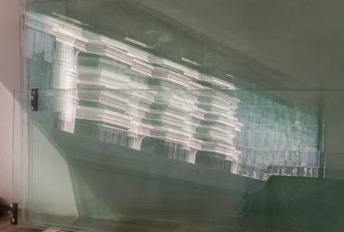 Bangkok, Tayland 23 Aralık 2024 - Çimento duvarına dayanan yansıtıcı cam üzerindeki modern yapı görüntüsü. Aynalı yüzeydeki binanın yansıması, bunu metin için duvar kağıdı, poster ve boşluk olarak kullanın, Seçici odak.