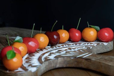 View of Traditional thai sweet treats made from mung beans and coconut milk, and glazed in shiny agar agar jelly. Deletable imitation fruits (Kanom look choup) in the shape of fruits has a sweet taste on wooden cutting board. Auspicious thai dessert, clipart