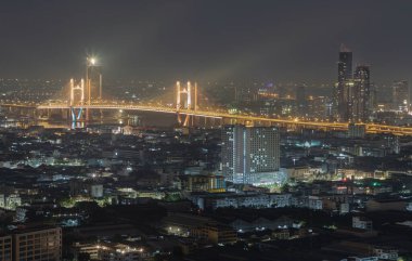 Bangkok, Tayland 31 Aralık 2024 - Thotsamarachan Köprüsü (Rama IX Köprüsü) ile Chao the Nehri 'ni geçen gökdelenlerin gece manzarası. Parlak ışıkları olan güzel şehir Bangkok 'u metin için duvar kağıdı, poster ve boşluk olarak kullanın..
