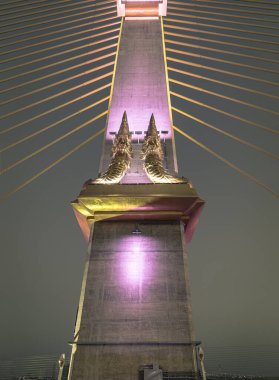 Bangkok, Thailand 10 Jan, 2025 - Two golden yellow Naga sculptures on concrete pillars of the King Rama X Bridge structure or Thotsamarachan Bridge with evening sky in the background. use it as your Wallpaper, Poster and Copy space, Selective focus. clipart