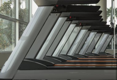 Bangkok, Tayland - 18 Ocak 2025 - Koşu bandının sabah görüş açısı ve spor salonunda güneş ışığı. Koşu bandı makinelerinin perspektif görünümü, metin, Seçici odak için duvar kağıdı, poster ve boşluk olarak kullanın.