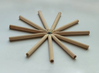 Kahverengi boya kalemleri gümüş arka planda daire şeklinde dizilmiş. Ahşap renkli kalemler biraraya gelip daire çizerler, renkli kalemlerin sanatsal bir gösterimi, çizim için kırtasiye malzemeleri, minimalizm sanat malzemeleri konsepti, metin, tasarım ve duvar için boş alan