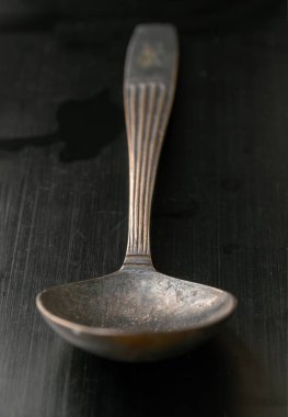 Eskiler 'in klasik kaşığının yüzey görüşü siyah arka planda izole edilmiş. Siyah eskimiş metal kaşık koyu tonda yakın plan, deseni ve tasarımını vurgulamak, metin, tasarım, duvar kağıdı ve poster için boşluk olarak kullanmak, seçici odak