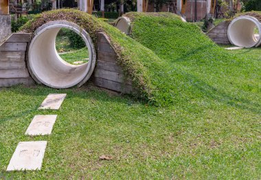 Bangkok, Tayland - 19 Şubat 2025 - Çocuk oyunu için yapılmış parkın beton tünel manzarası, sayısız oyuklarından saklanıyor. Çocuklar için parkın tepesinde çim tepeciği olan çocuk tüneli var.