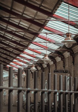 Beyaz tavandan sarkan cam küre gölgesi olan klasik bir bakır tavan lambası ve tahta kirişler Windsor & Eton Riverside tren istasyonunda kırsal ama zarif bir iç atmosfer yaratıyor. Paddington kolye ışığı. Uzayı kopyala