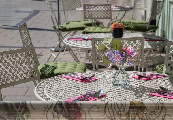 Windsor, İngiltere - Nisan 03, 2025 - Metal beyaz masa boyunca güneş ışığı ve öğleden sonra bir kafede klasik tarzda sandalyeler. Metin, Seçici odak için Duvar Kağıdı, Poster ve Boşluk olarak kullan.