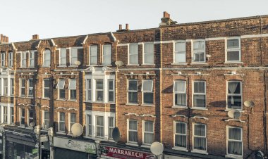 Londra, İngiltere - 06 Nisan 2025 - Londra 'daki apartmanların dış mimarisi. Klasik cam pencereli kırmızı tuğlalı bir binanın ön cephesi, Duvar kağıdı, Poster ve Kopyalama alanı olarak kullanın, Seçici odak.