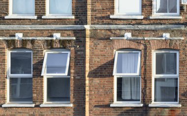 Londra, İngiltere - 06 Nisan 2025 - Güneş ışığı eski evin dışındaki cam pencere çerçevesinden içeri giriyor. Londra 'da cam pencere ve tuğla duvar, bunu duvar kağıdı, poster ve kopyalama alanı, seçici odak noktası olarak kullanın.