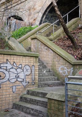 Newcastle, İngiltere - 13 Nisan 2025 - Stone stairs ve Brick, Tyne 'daki Newcastle Köprüsü' nün altında Graffiti ile birlikte yol alıyorlar. Metin, Seçici odak için Duvar Kağıdı, Poster ve Boşluk olarak kullan.