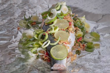 Alüminyum folyoyla pişirilmiş somon balığı hazırlayın. Malzemeler arasında kişniş kökü, Ginger, Galangal, Kaffir limonu, Leek, ve somon balığının üzerine dilimlenmiş limon dilimlenmiş kuş gözü biberi yer alıyor. Sağlıklı beslenme, metin için boşluk.